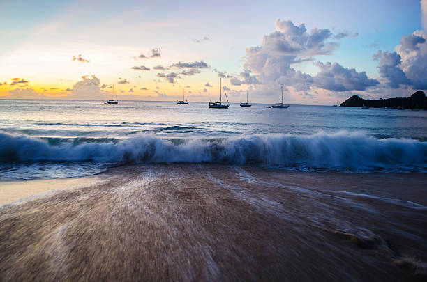 onda sulla spiaggia al tramonto con distante yacht - wave sea storm water foto e immagini stock