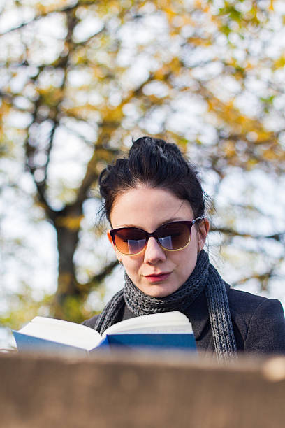 istock Young woman reading book in the park 174784581