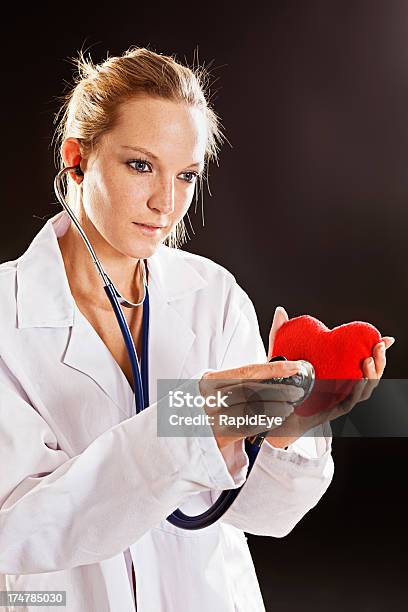 Серьезные Молодая Женщина Врач Проверяет День Святого Валентина Сердце С Стетоскоп — стоковые фотографии и другие картинки Женщины