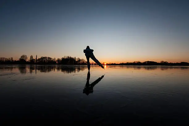 Photo of Outline of a person ice skating at dusk with gradient sky