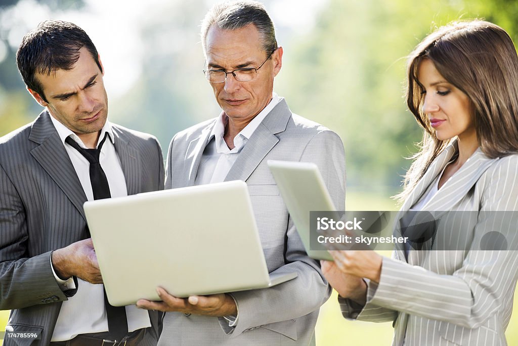 Tre uomini d'affari utilizzando la tecnologia wireless. - Foto stock royalty-free di Ambientazione esterna