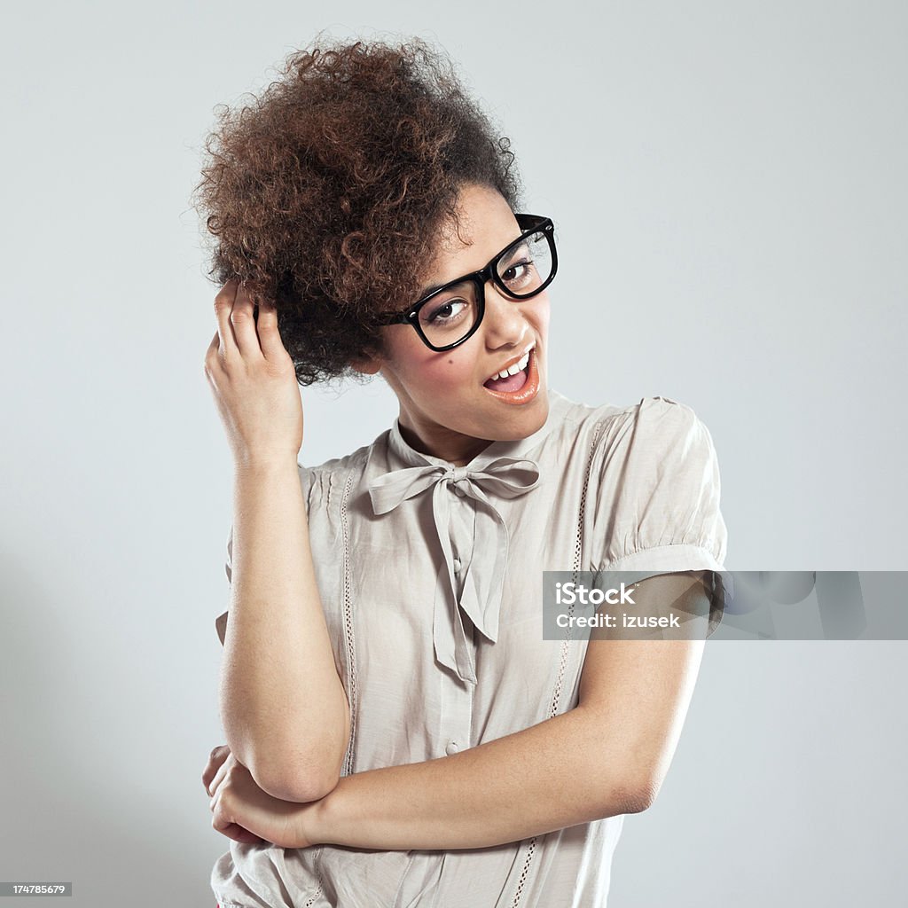 Cute Afro Girl Portrait of cute teenaged afro girl wearing nerd glasses, standing against grey background and laughing at the camera. 18-19 Years Stock Photo