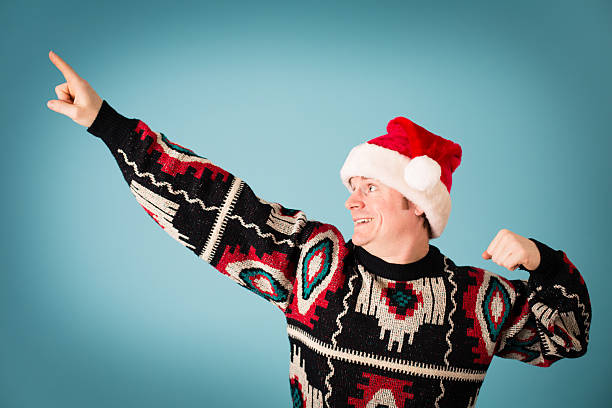 Man Rearing to Go, Wearing Santa Hat and Ugly Sweater "Color image of a man, wearing a Santa hat and an ugly sweater, excited to get going to party." ugliness photos stock pictures, royalty-free photos & images