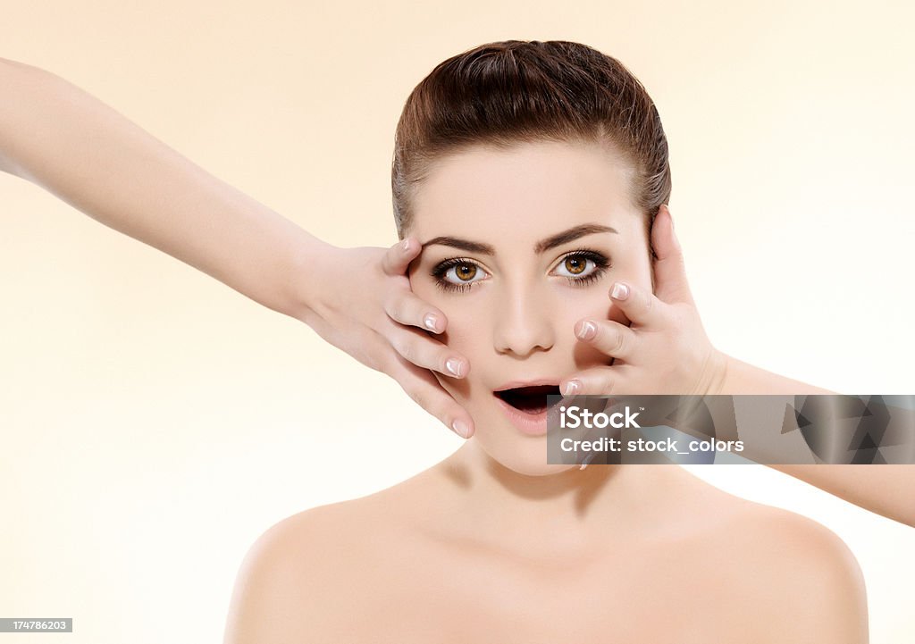 surprised woman young woman with hands on face being surprised, beige background. 20-24 Years Stock Photo