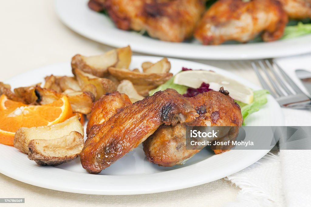 Ailes de poulet avec pommes de terre sautées et de la garniture sur une assiette - Photo de Aile d'animal libre de droits