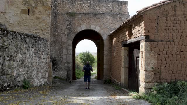 Man observes the ancient entrance of a medieval village in Maderuelo, Spain.
