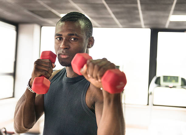 istock Young man doing exercise on a gym with dumbbell 174787841