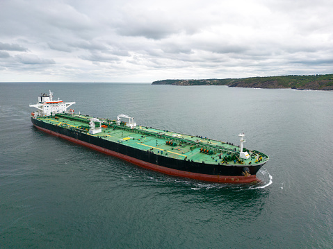 Huge green contaner ship under loading operation with blue gantry cranes in the port of Felixtowe