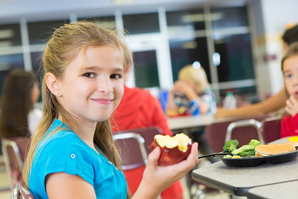 istock Happy elementary school student eating apple in cafeteria 174788911