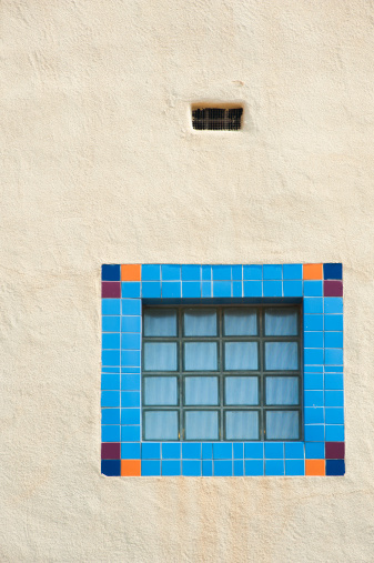 A modern Southwestern courtyard window adds some architectural flair with a brightly tiled frame set into a stucco wall.
