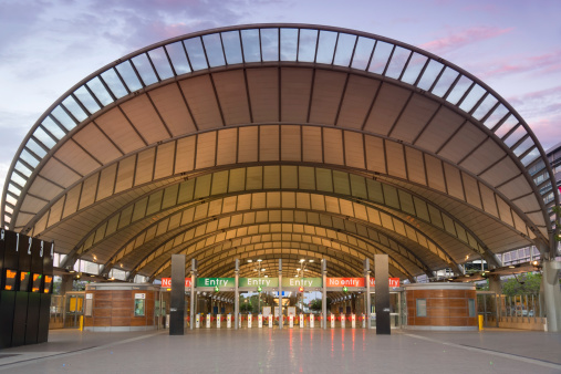 The modern train station at Sydney Olympic Park, seen at dusk under a colourful sky.