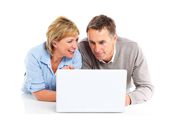 Happy senior couple lying on floor using laptop computer Happy senior couple lying on floor using laptop computer over white background woman lying on the floor isolated stock pictures, royalty-free photos & images