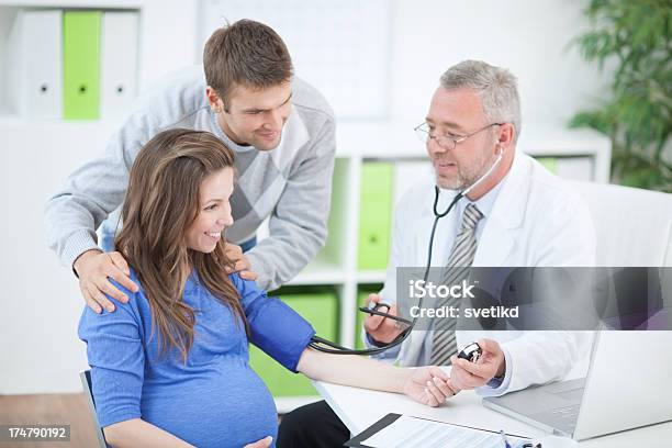 Mujer Embarazada Con Marido En Consultorio Médico Foto de stock y más banco de imágenes de 50-59 años - 50-59 años, Adulto, Adulto maduro