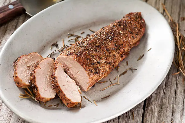 Pork tenderloin on a platter with knife rosemary and peppercorns.  Please see my portfolio for other food related images.