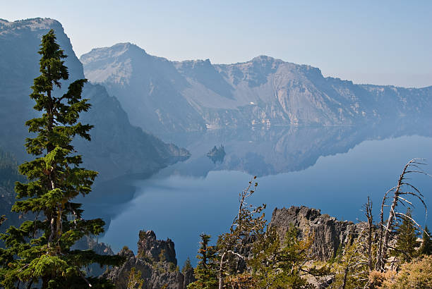 Crater Lake and Phantom Ship Rock Formation Crater Lake exists in the blown-out caldera of a once mighty volcano known as Mount Mazama. This view of the lake was taken from East Rim Drive in Crater Lake National Park, Oregon, USA. jeff goulden crater lake national park stock pictures, royalty-free photos & images