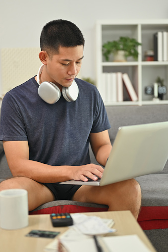 Concentrated male freelancer working online or browsing web on laptop at home.