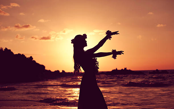 Beautiful Young Hula Dancer Young Hula Dancer posing for the camera seaside at sunset time backlit. hula dancer stock pictures, royalty-free photos & images