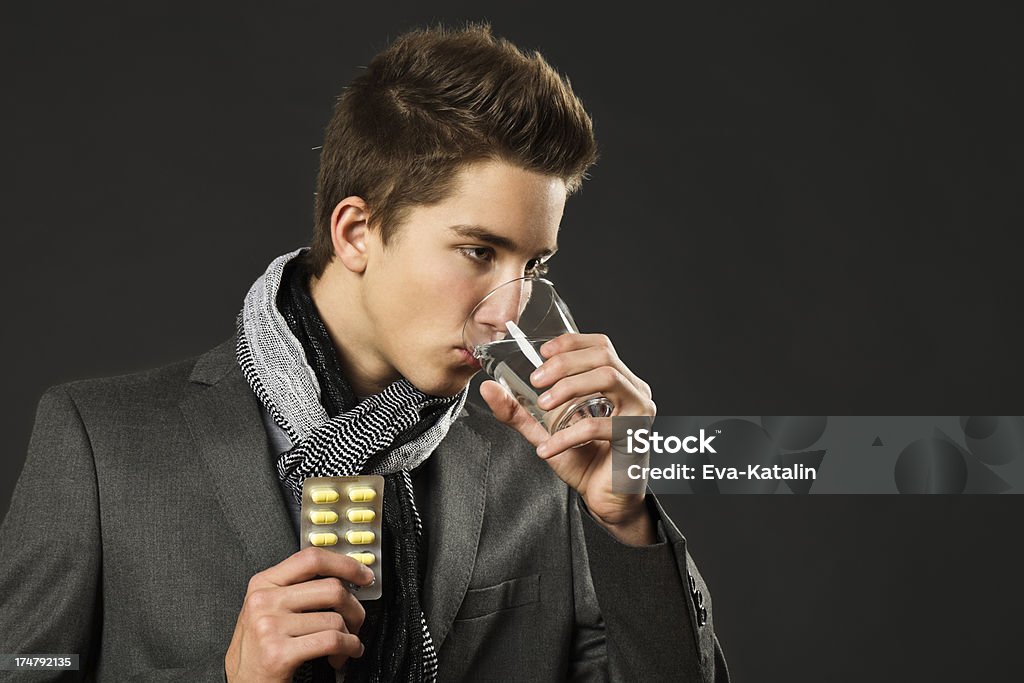 Teenage boy toma una píldora - Foto de stock de Invierno libre de derechos