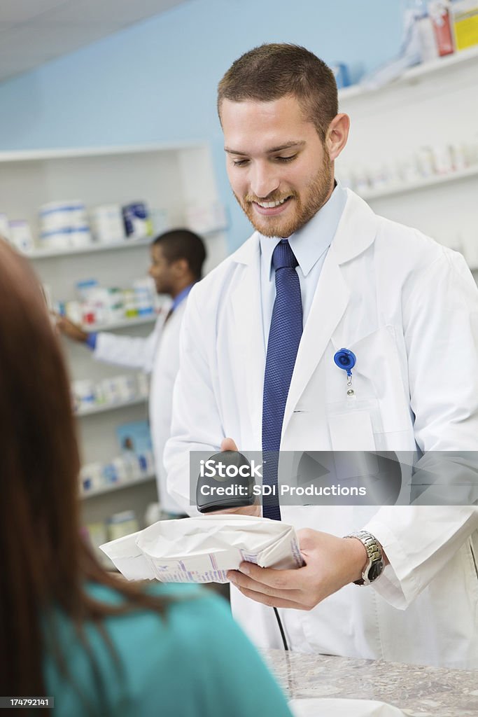 Farmacéutico mediante el uso de un escáner de check-out en la prescripción de farmacia cliente - Foto de stock de Adulto libre de derechos
