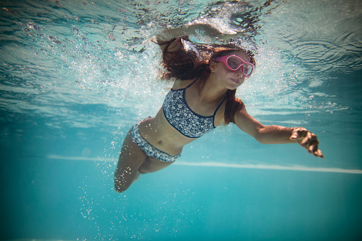 Underwater portrait of a teenage girl swimming in a swimming pool\nShot with Nikon D810