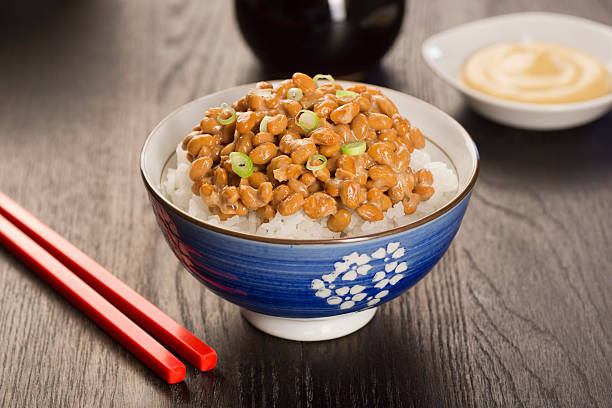 Natto (Fermented Soybeans) Natto is a Japanese dish made from fermented soybeans. It has a distinctive smell and sticky, stringy texture. It is frequently served over rice, topped with sliced green onions with mustard and soy sauce. natto stock pictures, royalty-free photos & images