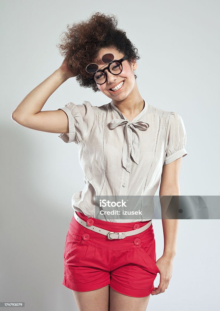 Cute Girl Portrait of cute teenaged afro girl wearing funny glasses and laughing at the camera. Studio shot, grey background. 18-19 Years Stock Photo
