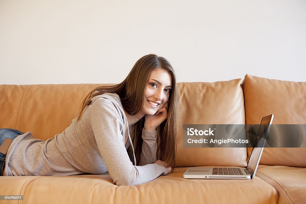 Mujer joven con ordenador portátil en el sofá - Foto de stock de Acogedor libre de derechos
