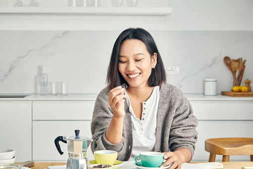 Portrait of a cute and happy young girl in the kitchen, early bird morning routine, drinking coffee, representing positive attitude and a healthy lifestyle, an image with a large copy space