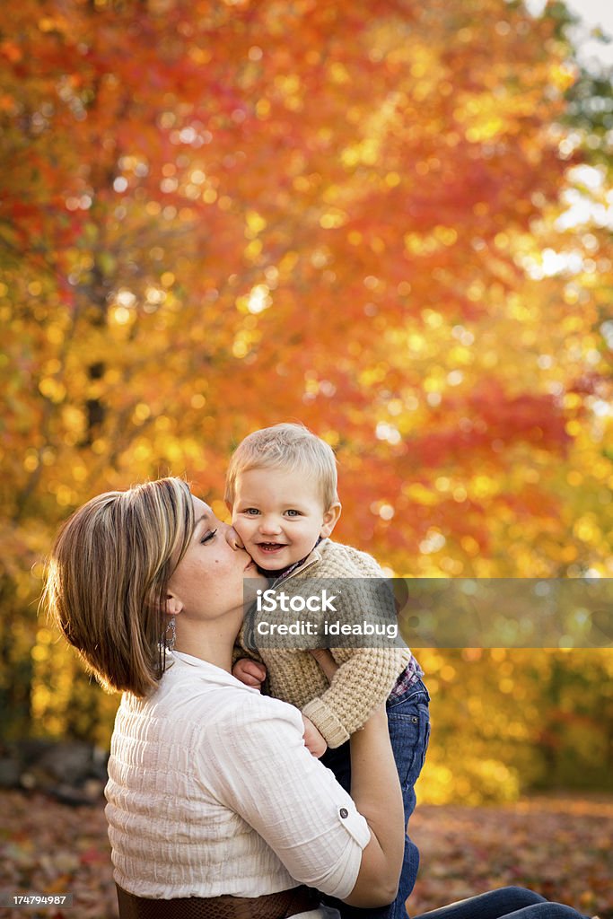 Mãe beijando o filho pequeno enquanto do lado de fora em um dia de outono nos EUA - Foto de stock de 18 a 23 meses royalty-free