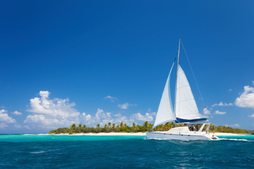 catamaran sailing close by a tropical island in the Caribbean