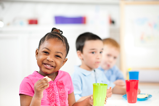 diverse group of preschool children eating their snacks