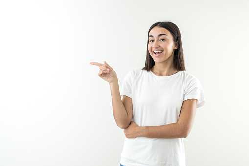 Happy girl offering and presenting a product or message over hand in empty space copy. With short hair green sweater and jeans.Looking at camera