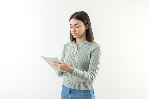 Young girl with short hair looking at tablet. She reads the information. Green sweater and jeans