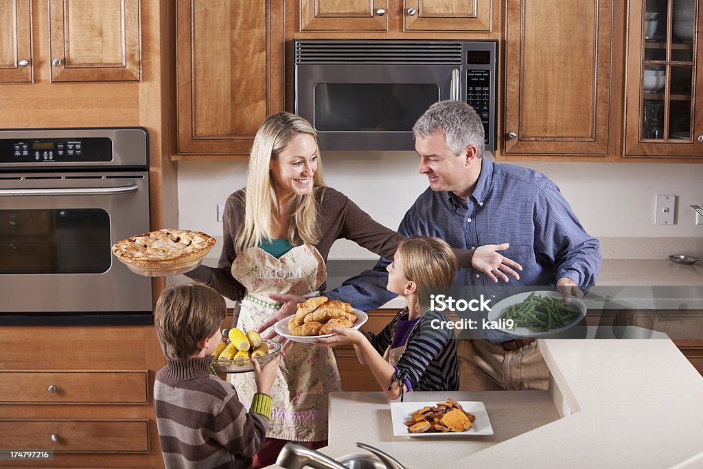 Семья на кухне, помогая матери служить ужин - Стоковые фото Семья роялти-фри