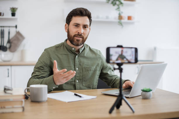 istock Man working on laptop and recording video on smartphone 1747983051