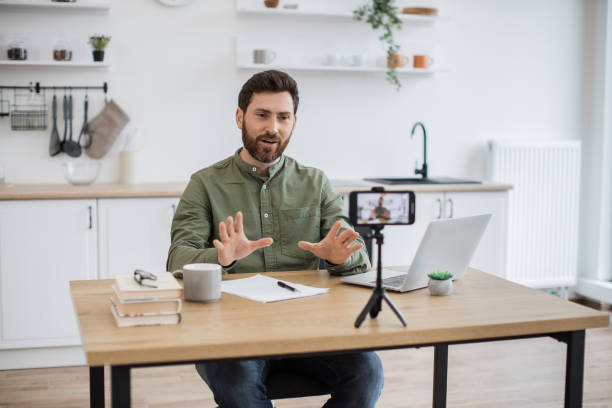istock Man working on laptop and recording video on smartphone 1747983137