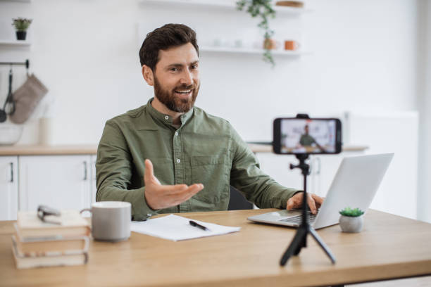 istock Man working on laptop and recording video on smartphone 1747983138