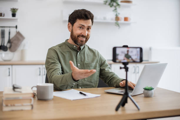istock Man working on laptop and recording video on smartphone 1747983152