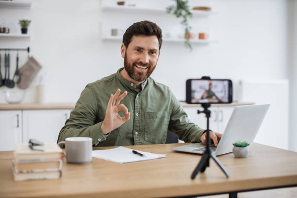 istock Man working on laptop and recording video on smartphone 1747983155