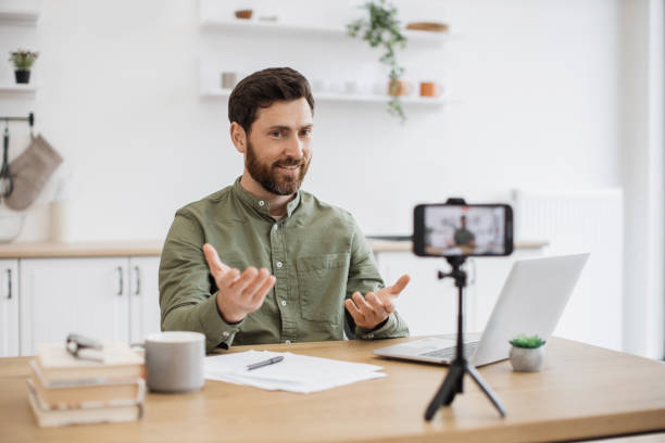 istock Man working on laptop and recording video on smartphone 1747984242