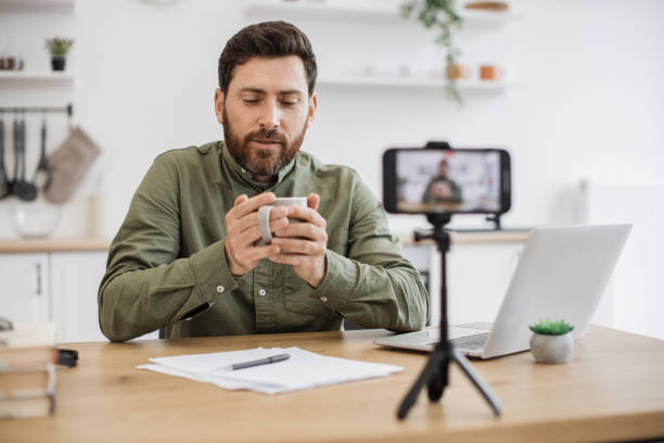istock Unwell man vlogger filming blog and drinking tea from mug 1747984754