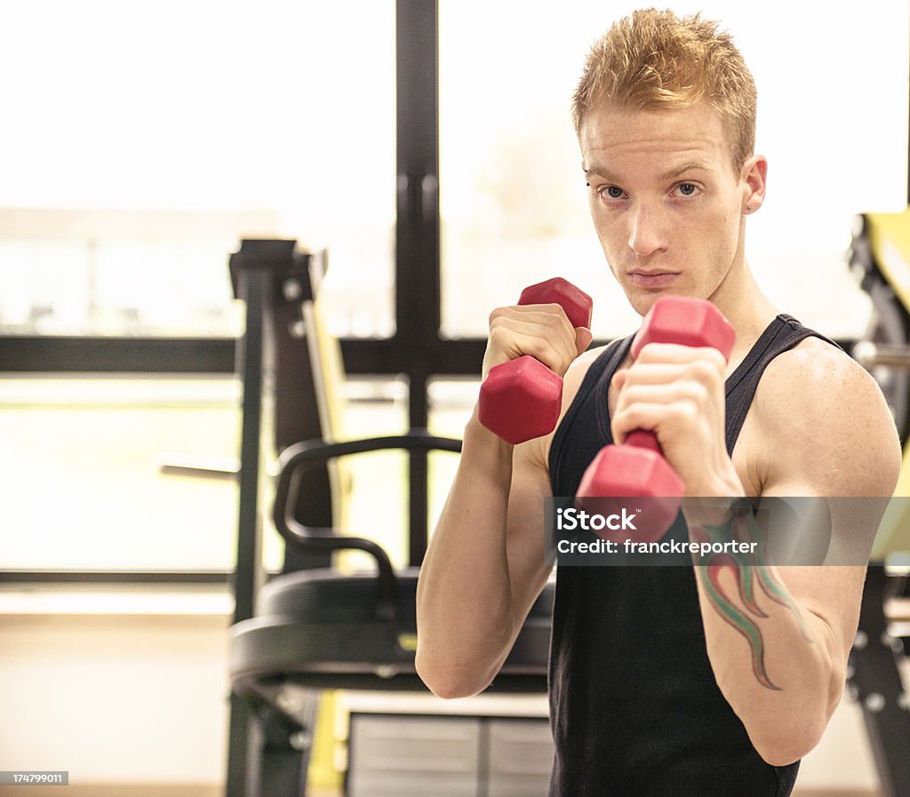 Joven haciendo ejercicio en el gimnasio con pesa - Foto de stock de 20 a 29 años libre de derechos