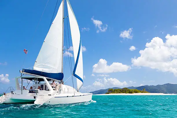 catamaran sailing close by a tropical island in the Caribbean