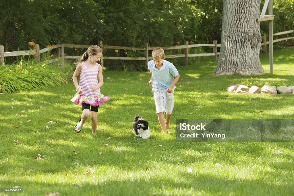 Giovani Bambini che giocano con la famiglia animali domestici cane in cortile - Foto stock royalty-free di Cane