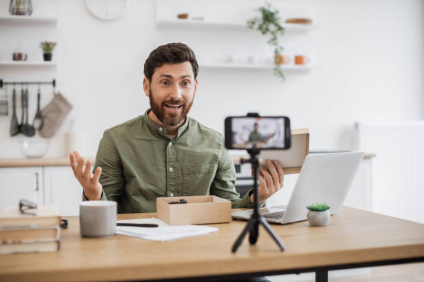 istock Surprised vlogger unpacking box and filming video on mobile 1748016275