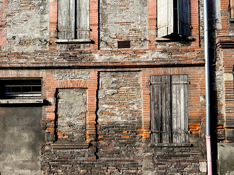 Facade of an old house with broken windows and a crack in the wall