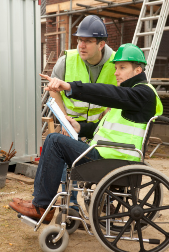 Disabled man in wheelchair at work by a building site If you want more images with a man in wheelchair please click here.