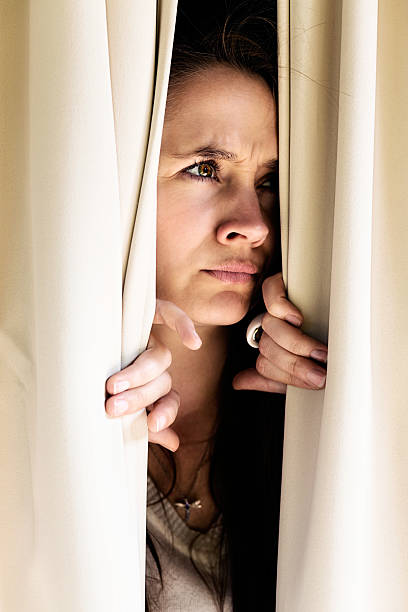 istock Suspicious blonde peeps through curtains, not liking what she sees 174802999