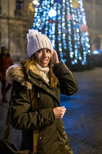 Half-length portrait of smiling posing girl with Christmas tree in the background in Pamplona, Spain