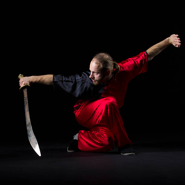 шаолинь кунг-фу борьбе с позиции с dao меч на черный - wushu skill action aggression стоковые фото и изображения